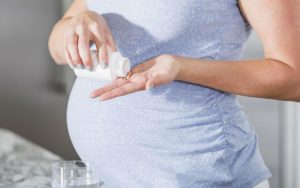Женщина пьёт таблетки во время беременности