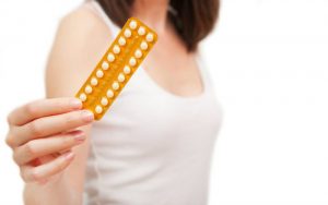 Женщина держит в руках упаковку противозачаточных таблеток