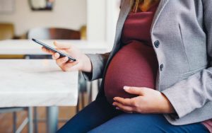 Беременная женщина смотрит в смартфон