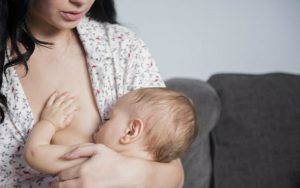 Женщина кормит младенца грудью