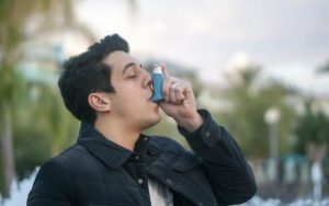 Мужчина пользуется аэрозольным ингалятором от астмы