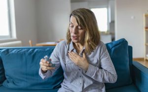 Женщина использует ингалятор для лечения астмы