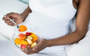 Беременная женщина кушает фрукты