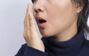 Женщина оценивает запах из своего рта