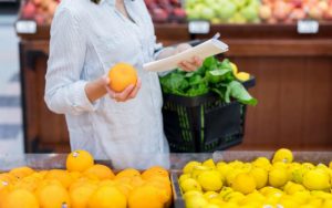 Женщина покупает цитрусовые фрукты на рынке