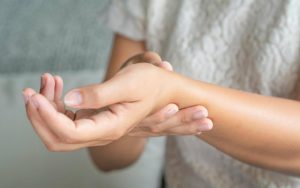 Женщина держится за руку, поражённую ревматоидным артритом