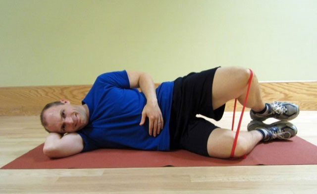 упражнение для коленей с эластичной лентой лежа на боку