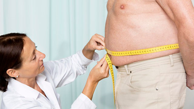 врач измеряет талию у мужчины с лишним весом